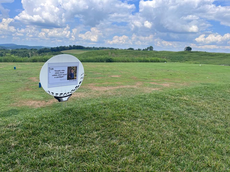 Photo of the 18th tee box at Birdsfoot, showcasing the tee sign with Dayna's photo on it as well as a beautiful sky in the background